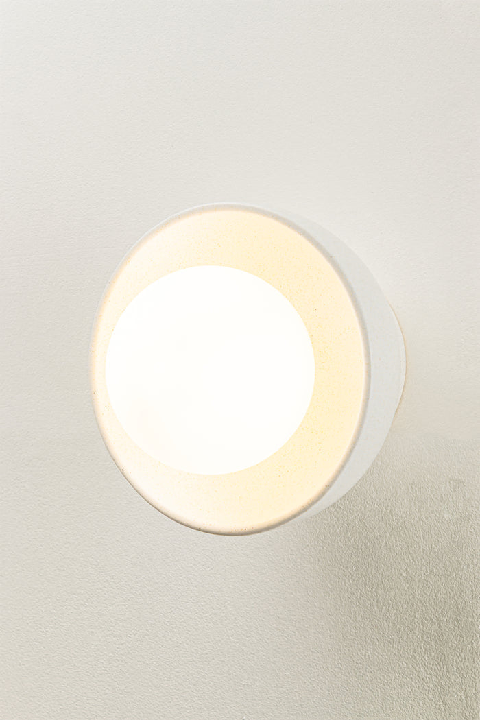 Casting warm diffused light through its opal glass orb on ceramic shade