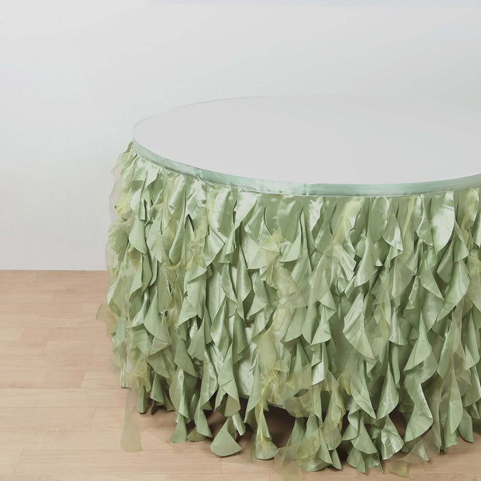 Green ruffled table skirt on a round table against a plain background.