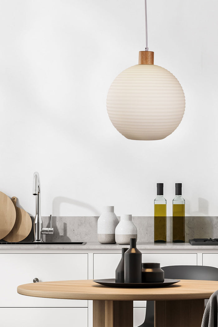 Large round, opal glass shade with ripple effect and timber detailing, over a dining space.