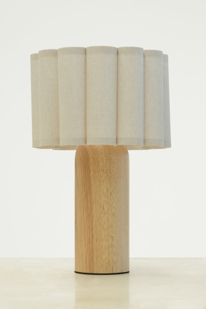 Natural fabric shade with scalloped detailing paired with a curved wood block table lamp base.