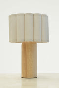 Natural fabric shade with scalloped detailing paired with a curved wood block table lamp base.