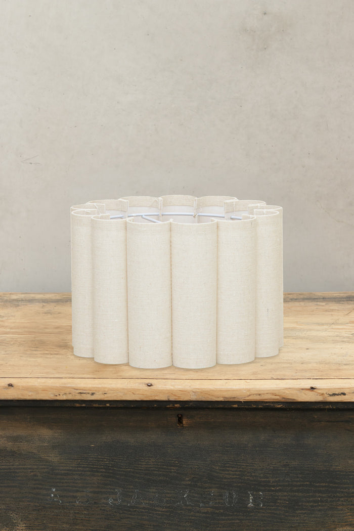Single tiered scalloped fabric shade with a natural finish, sitting on a timber bench.