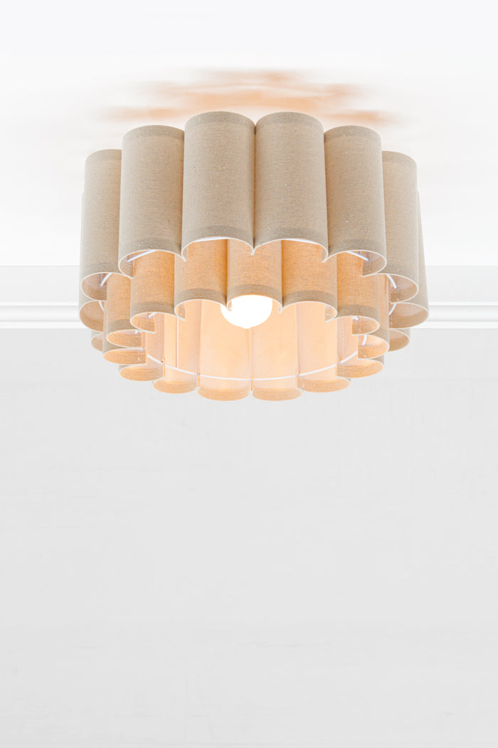 Neutral toned fabric shade with two teirs in a scallopped formation, paired with an opal bulb.