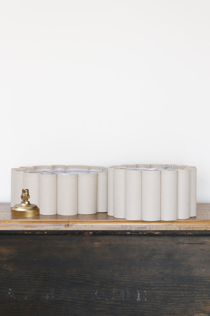 Uninstalled neutral toned scalloped shades with gold/brass batten holder.