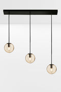 Three drop linear light with amber glass ball shades and black hardware.