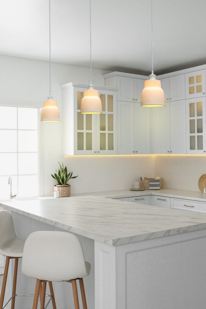 Ridged ceramic shade with white cord in set of three above kitchen bench