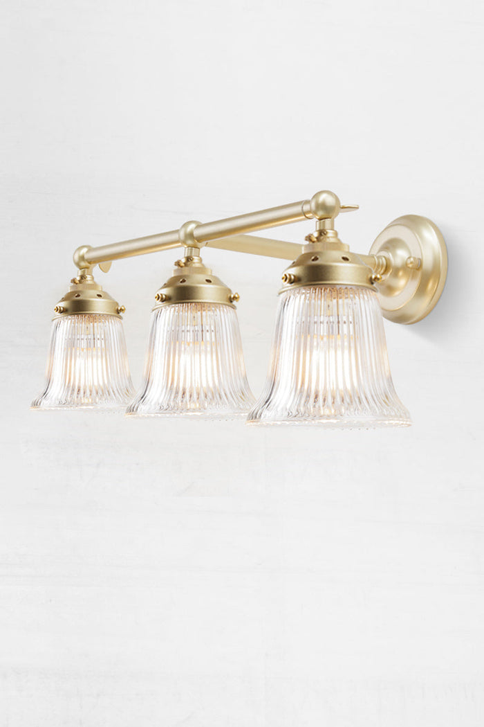 Gold/brass wall sonce with clear reeded glass shades.