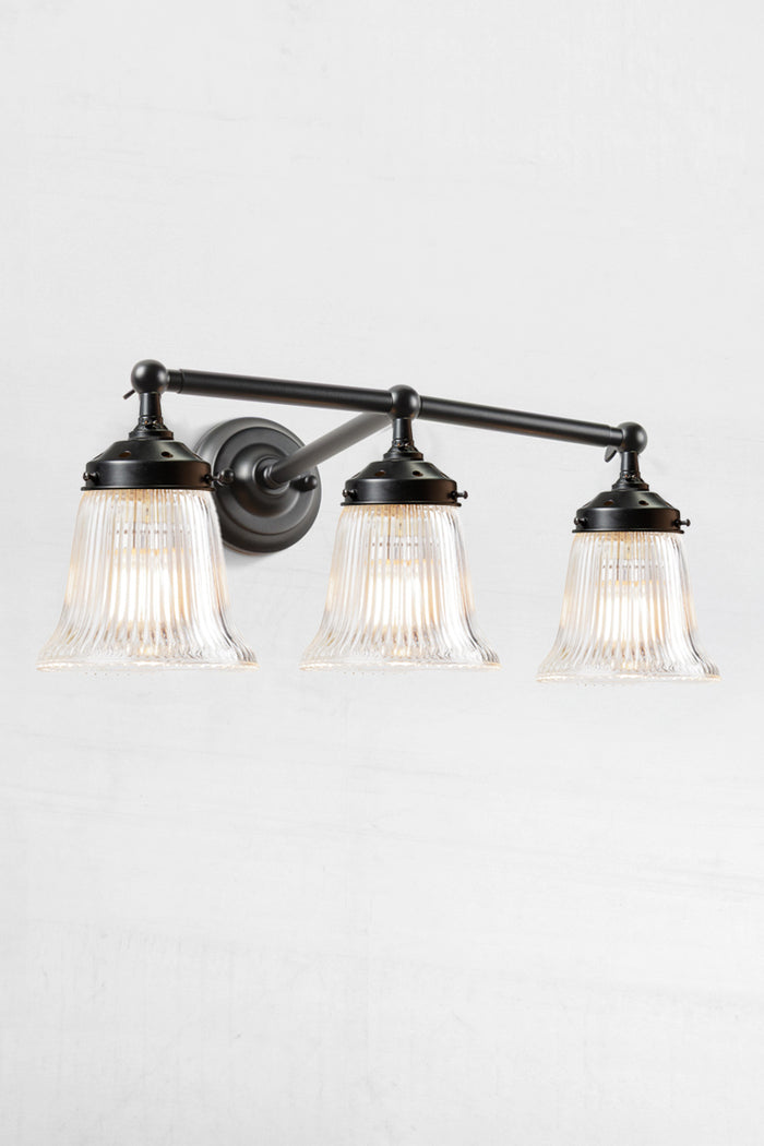Black wall sonce with three clear reeded glass shades.