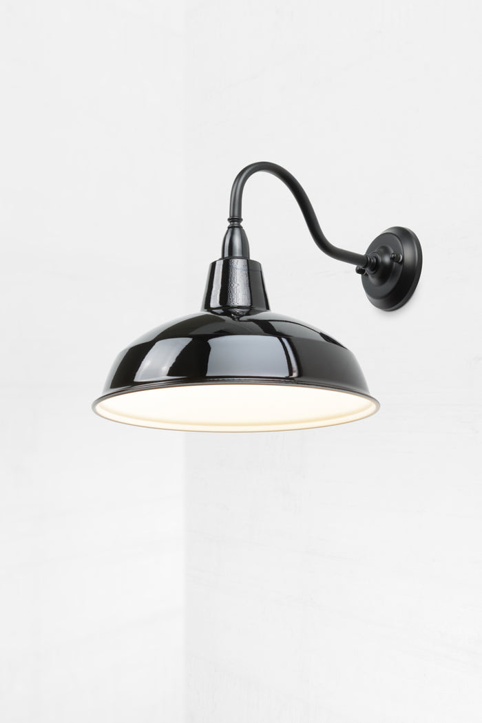 Small warehose shade in black on a large outdoor gooseneck wall sconce, showcasing white inner.