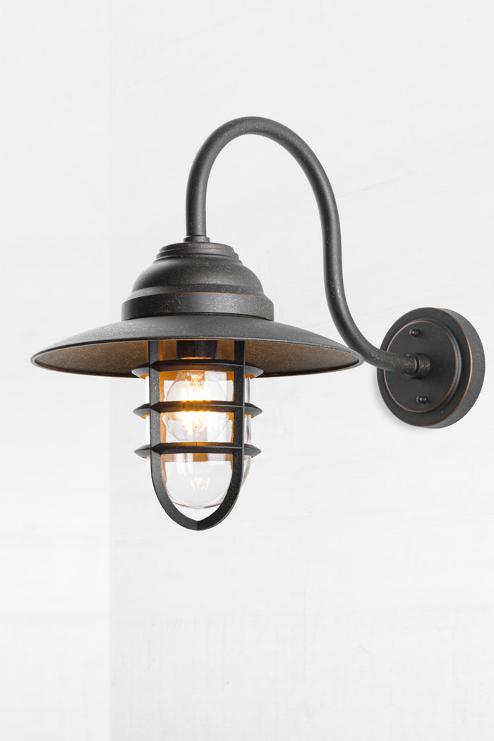 Nautical designed wall light with an antique bronze finish, cage and glass guard.