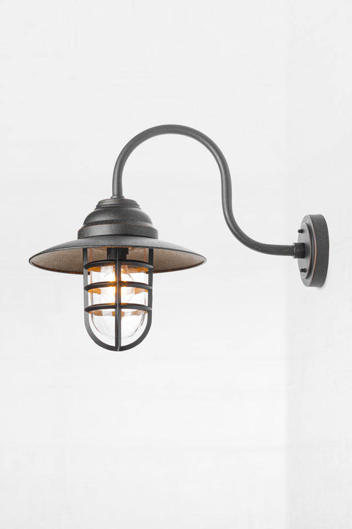Close up of the antique brass wall light with gooseneck arm and shade.